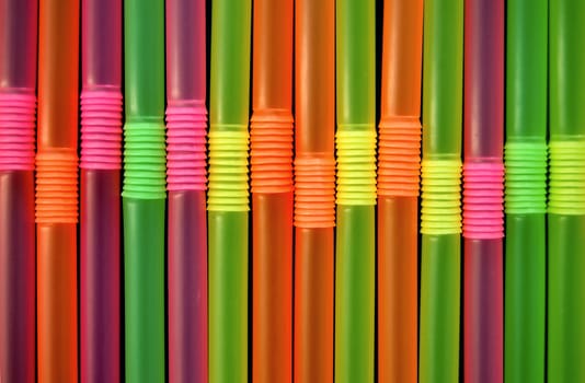 Drinking straws against a black background. Abstract pattern.