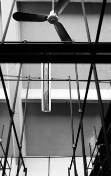 Ceiling fan and empty shelves inside an abandoned factory. Black and white.