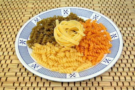 Plate with three flavors of fusilli pasta. Italian food background.