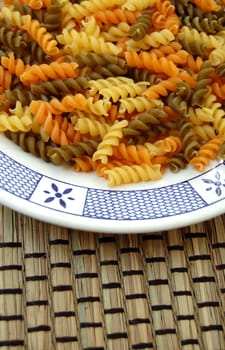 White plate with three flavors of fusilli pasta. Italian food background.