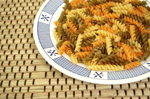 Three different flavors of fusilli pasta. Italian food background.