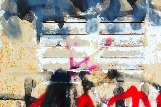 Detail of rusty metal surface covered with messy graffiti.