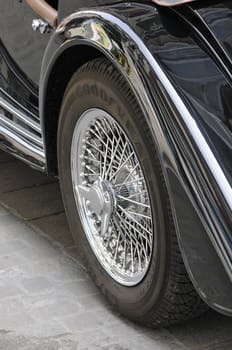 Chromed back wheel on a black Morgan car