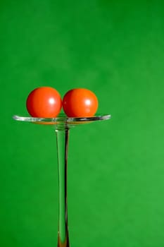 Two small red tomatoes on green background