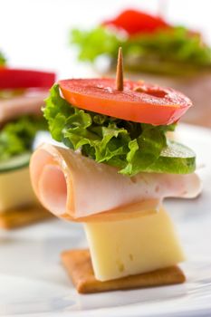 food theme: cracker with ham, cheese and vegetables on the plate