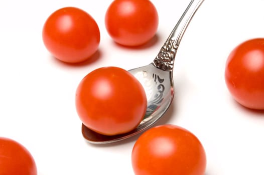 Red tomatoes on white background and teaspoon