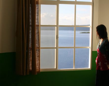 Lonely girl in melancholy looking in window