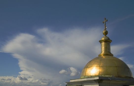 Cold dome of a temple and while clouds