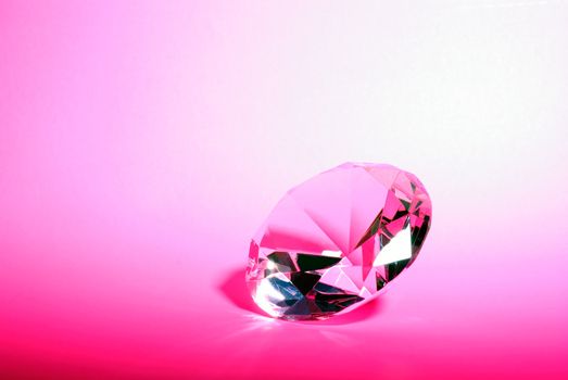 Horizontal Image of a Pink Gemstone in a Brilliant Diamond Cut Against a Pink Background