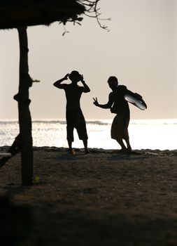 Two men - surfers on a sunset on Bali