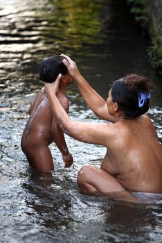 Mother bathes the child in the river. Indonesia. Bali