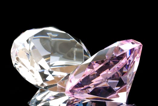 Horizontal Image of a Colored and a Clear Diamond Cut Gems Against a Black Background