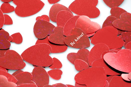 Horizontal image of red hearts against a white background.  One of the central hearts has the words - "Be Mine" on it.