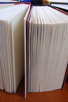 Vertical image of a group of books standing up in a circular formation on a wooden table.