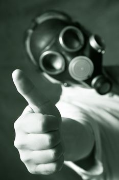 The person in a gas mask. A hand in a zone of sharpness, the rest is dim