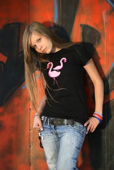 The young girl on a background of a wall with graffiti
