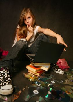 The young girl among books with a computer