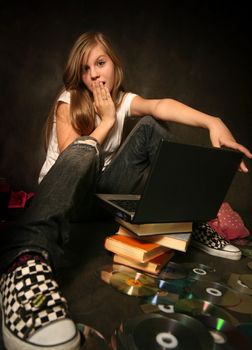The young girl among books with a computer