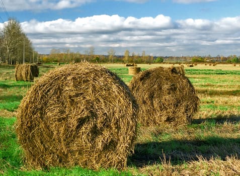 Autumn field with two rolls of hay on the foreground
