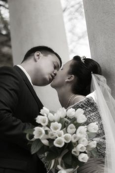 Beautiful the bride and the groom kiss at columns