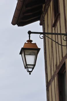 Old style metallic lantern on a bask house wall with a cloudy sky