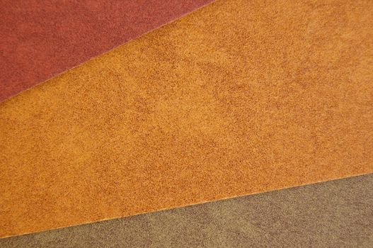 Three different colors of recycled paper. Speckled cardboard background texture.