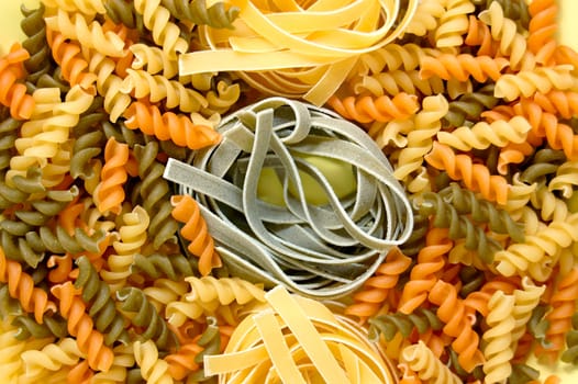 Three different flavors of fusilli and tagliatelle pasta. Italian food background.