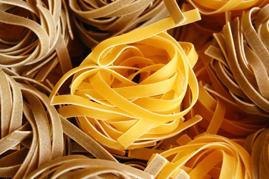 Two flavors of fresh tagliatelle pasta. Italian food background.