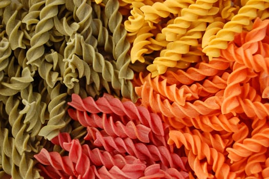 Four different flavors of twirls pasta. Italian food background detail.