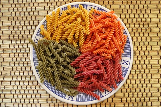 Plate with four flavors of fusilli pasta. Italian food background.