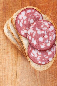 Slices of sausage on a bread on a wood board