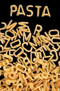 Spelling of the word pasta with alphabet soup letters. Kids food background.