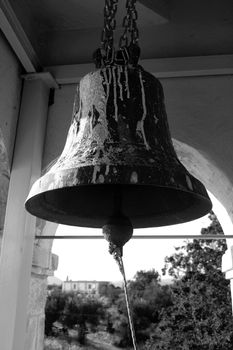 Rusty bell inside an old belfry in a village in Greece. Black and white.
