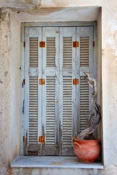 Weathered window shutter and decorative pottery. Traditional Greek island house detail.