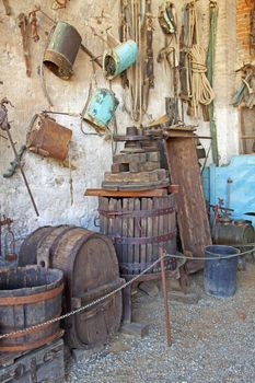 Old press for grape in between other rural tools