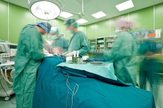 Blurred figures with medical uniforms performing surgery in operative room