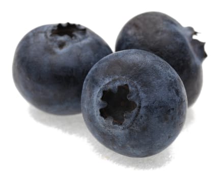 A group of three blueberries photographed in a studio against a white background.Selective focus on the closest blueberry.