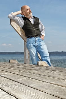 An old man with a grey beard relaxing at the lake