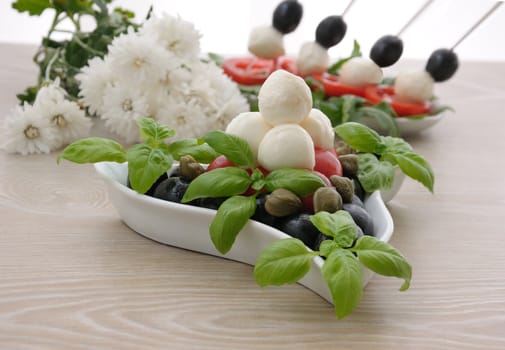 Appetizer of mozzarella, cherry tomatoes and olives, basil and capers