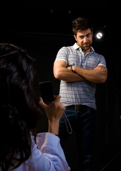 Girl taking photos of her boyfriend in a studio environment