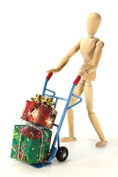 many colorful Christmas presents on a hand truck with wooden figure