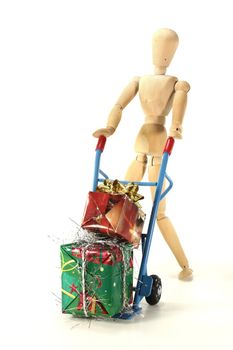 many colorful Christmas presents on a hand truck with wooden figure
