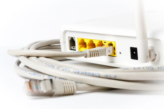 A router in top of an ethernet cable. Focus on the plug connected to the router.