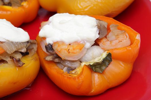 Stuffed pepper with shrimps, mushrooms and onion on red plate