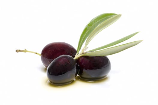 three fresh olives bathed in olive oil on white background