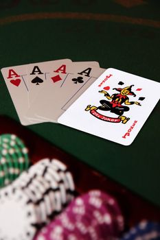 green casino table with chips and four aces in a poker game and a joker in the pack