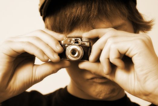 A young male holds a vintage spy camera in position to take a picture.