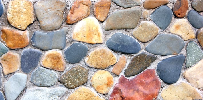 Stone wall of the house from different color of stones in a laying