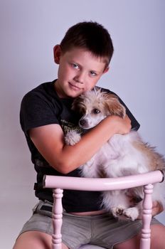 Young boy and dog. Portrait in studio on a grey background.
