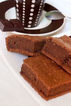 Pieces of chocolate cake on a plate with a cup of coffee in background